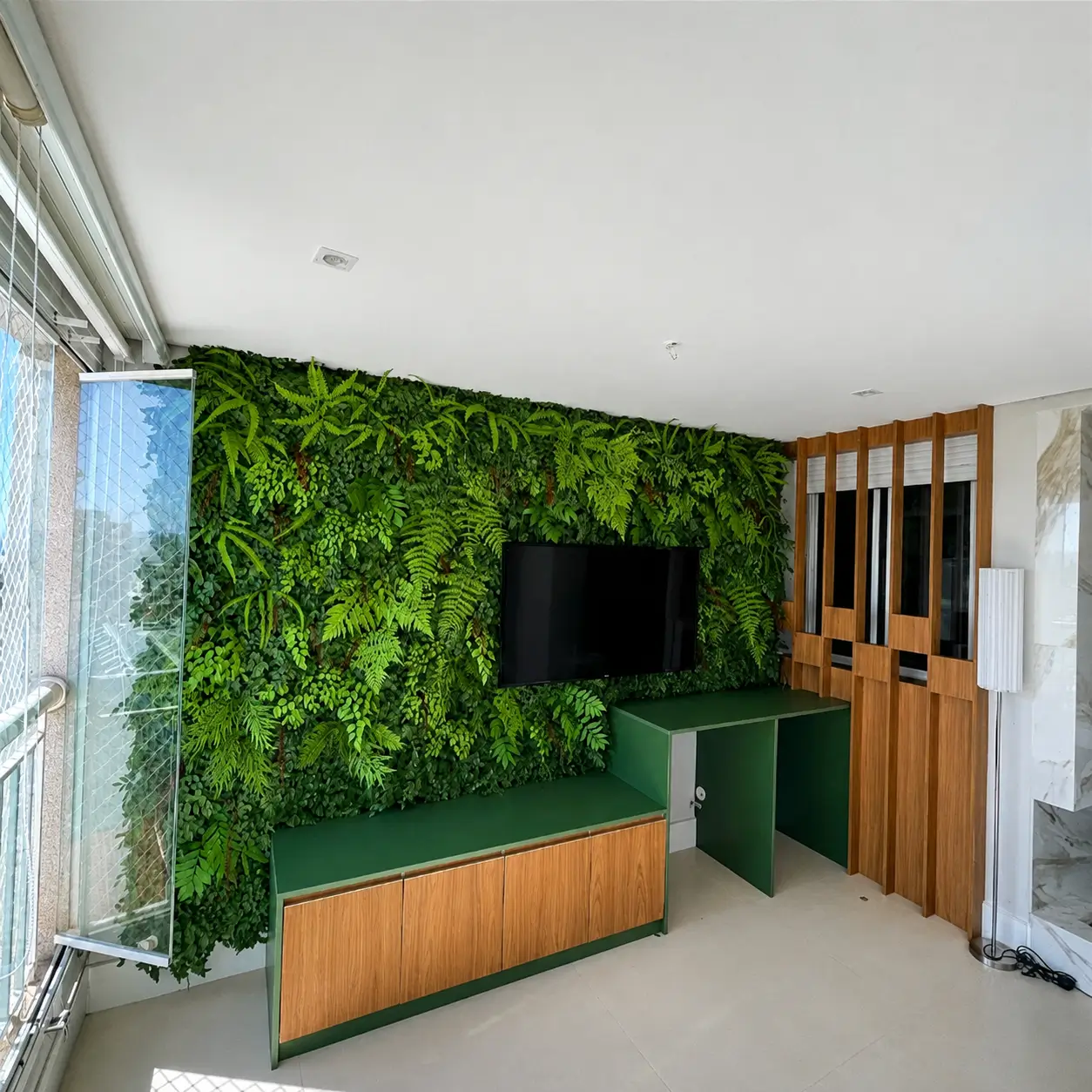 Varanda com parede verde, TV e marcenaria verde